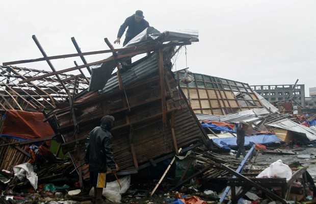 Homem é visto no topo de uma casa destruída em Tacloban, após passagem do tufão nas Filipinas (Foto: AFP)